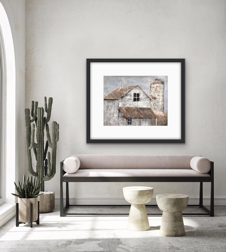May include: A framed painting of a weathered farmhouse with a silo, painted in muted tones of brown, gray, and white. The painting is displayed on a wall above a light pink bench with black metal legs.