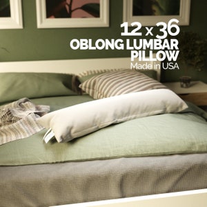 May include: A white oblong lumbar pillow on a green bed with a striped pillow. The pillow is 12 x 36 inches and made in the USA.
