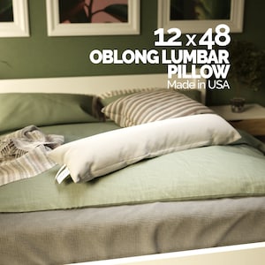 May include: A white oblong lumbar pillow on a green bed with a striped pillow. The pillow is 12 x 48 inches and says "Oblong Lumbar Pillow" and "Made in USA".