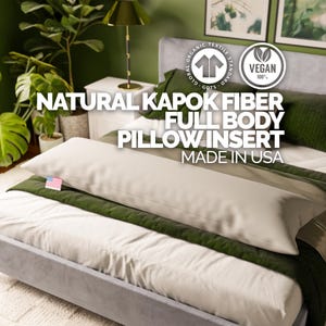 May include: A full body pillow insert made of natural kapok fiber, displayed on a bed with green and white bedding. The pillow is a light beige color and is labeled "Natural Kapok Fiber Full Body Pillow Insert Made in USA."