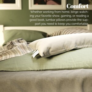 May include: A white lumbar pillow on a green bed with a striped throw blanket. The text "Comfort" is at the top of the image. The text below reads "Whether working from home, binge watching your favourite show, gaming, or reading a good book, lumbar pillows provide the support you need to keep you comfortable."