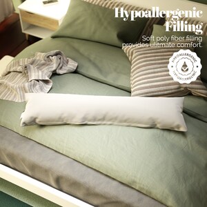 May include: A white hypoallergenic body pillow with a green and grey bedspread. The text "Hypoallergenic Filling" is displayed above the pillow. The text "Soft poly fiber filling provides ultimate comfort." is displayed below the pillow. A hypoallergenic seal is displayed below the text.