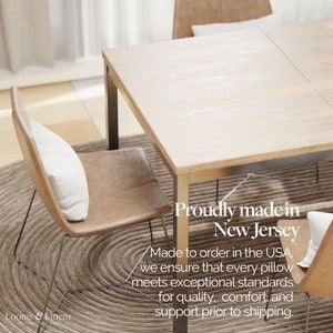 May include: A wooden dining table with two chairs. The table has a light wood finish and the chairs have brown leather seats. The text "Proudly made in New Jersey" is visible on the table. The text "Made to order in the USA, we ensure that every pillow meets exceptional standards for quality, comfort, and support prior to shipping." is also visible on the table.