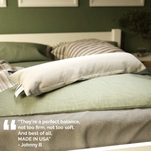 May include: A white body pillow on a green bed with a quote about the pillow: "They're a perfect balance, not too firm, not too soft. And best of all, MADE IN USA" - Johnny B