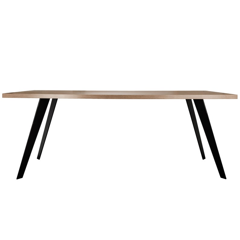 Op de afbeelding: Een rechthoekige houten tafel met zwarte metalen poten. De tafel heeft een lichtbruin houten blad en de poten zijn schuin.