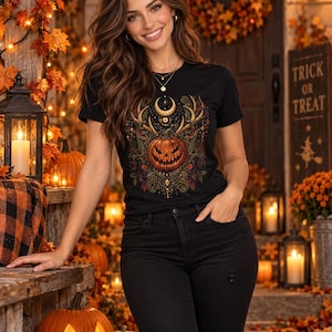 Peut inclure: Un t-shirt noir à manches courtes orné d'un motif central représentant une citrouille sculptée entourée de motifs tourbillonnants complexes, de bois de cerf et d'un croissant de lune, porté avec un jean noir à genou usé.