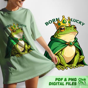 Pode incluir: Camiseta verde claro com um sapo de desenho animado usando uma coroa de ouro e uma capa verde. O texto "BORN LUCKY" está arqueado acima do sapo. A imagem também inclui o texto "PDF & PNG DIGITAL FILES".