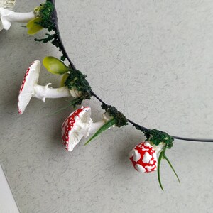 May include: A black headband with red and white mushroom charms and green foliage accents.