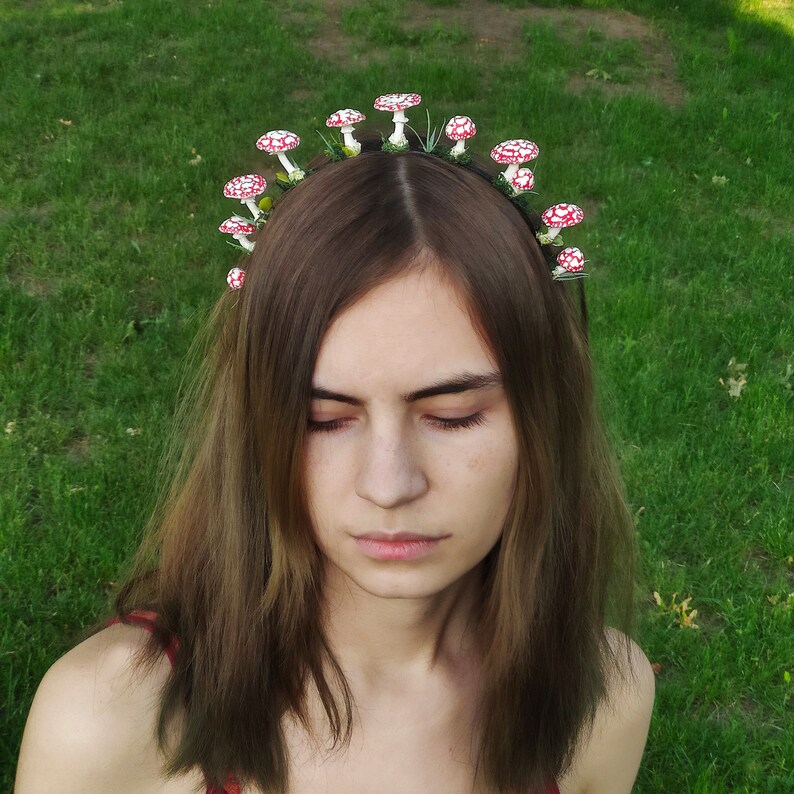 May include: A woman with long brown hair wearing a headband with red and white mushroom decorations.