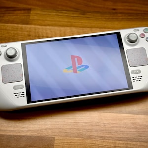 以下が含まれることがあります： PlayStationのロゴが表示された画面を持つ白いハンドヘルドゲームコンソール。コンソールには、円形の制御パッド、ボタン、スピーカーがあります。