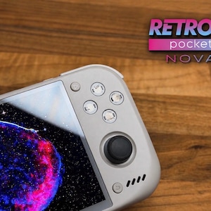 May include: A light gray handheld gaming console featuring a black joystick, four circular buttons labeled with directional arrows, and a power button. The screen displays a vibrant nebula image. The text RETROID pocket NOVA is visible.