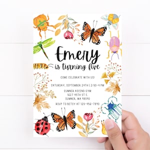 May include: A white invitation card with a watercolor design of butterflies, ladybugs, and other insects. The text on the card reads "Emery is turning five" and includes details for a birthday party.