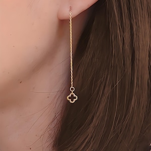Peut inclure: Boucles d'oreilles pendantes dorées avec un petit charme trèfle à la fin de la chaîne.