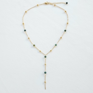 May include: A gold chain necklace with green gemstone beads. The necklace has a Y-shaped design with a longer strand extending from the center.