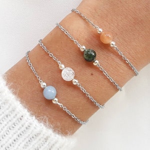 Peut inclure: Quatre bracelets en chaîne argent avec des perles de pierres précieuses de différentes couleurs. Les bracelets présentent une perle bleu clair, transparente, verte et orange.