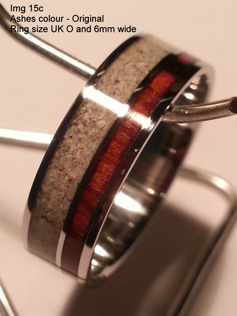 May include: A silver ring with a red and white inlay. The ring is 6 mm wide and is size UK O.