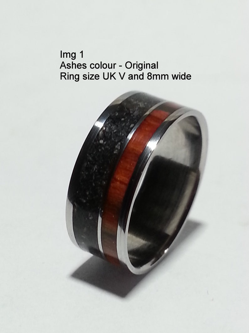 May include: A silver ring with a black and red inlay. The ring is 8mm wide and is a UK size V.