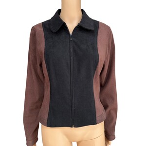 May include: A brown and black zip-up jacket. The jacket has a black center panel and brown side panels. It features a collared neckline and long sleeves. The jacket is made of a soft material.