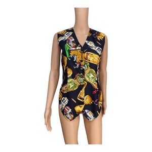 May include: A sleeveless, black romper with a V-neck and a colorful print featuring gold goblets, bottles, and other decorative elements. The romper has a button-up front and a unique, patterned design.