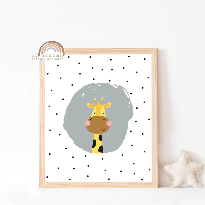 May include: A framed print featuring a cartoon giraffe with a yellow body, brown face, and pink cheeks. The giraffe is set against a gray circle on a white background dotted with black circles. The frame is light brown.