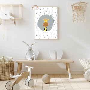May include: A framed wall art print featuring a cartoon giraffe with a yellow body, brown face, and black spots. The giraffe is set against a light blue circle on a white background with black polka dots. The print is in a light wood frame.