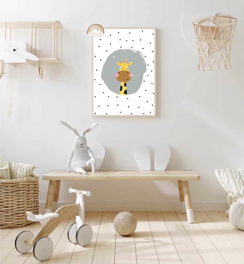 May include: A framed wall art print featuring a cartoon giraffe with a yellow body, brown face, and black spots. The giraffe is set against a light blue circle on a white background with black polka dots. The print is in a light wood frame.