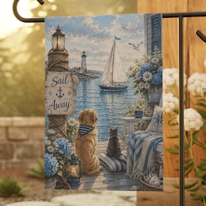 May include: A garden flag featuring a coastal scene with a lighthouse, sailboat, and the text "Sail Away." A golden retriever and a black cat are depicted on a wooden dock. The flag is displayed on a black metal stand, surrounded by greenery.