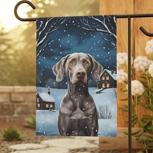 May include: A garden flag featuring a black and gray German Shorthaired Pointer dog sitting in a snowy winter scene with houses in the background.