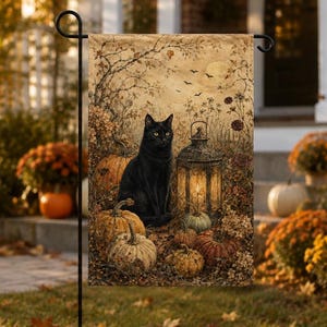 May include: A rectangular garden flag featuring a black cat sitting next to a lit lantern surrounded by various pumpkins and autumn foliage. The scene is set against a muted, textured background with bare tree branches and a soft, glowing moon.