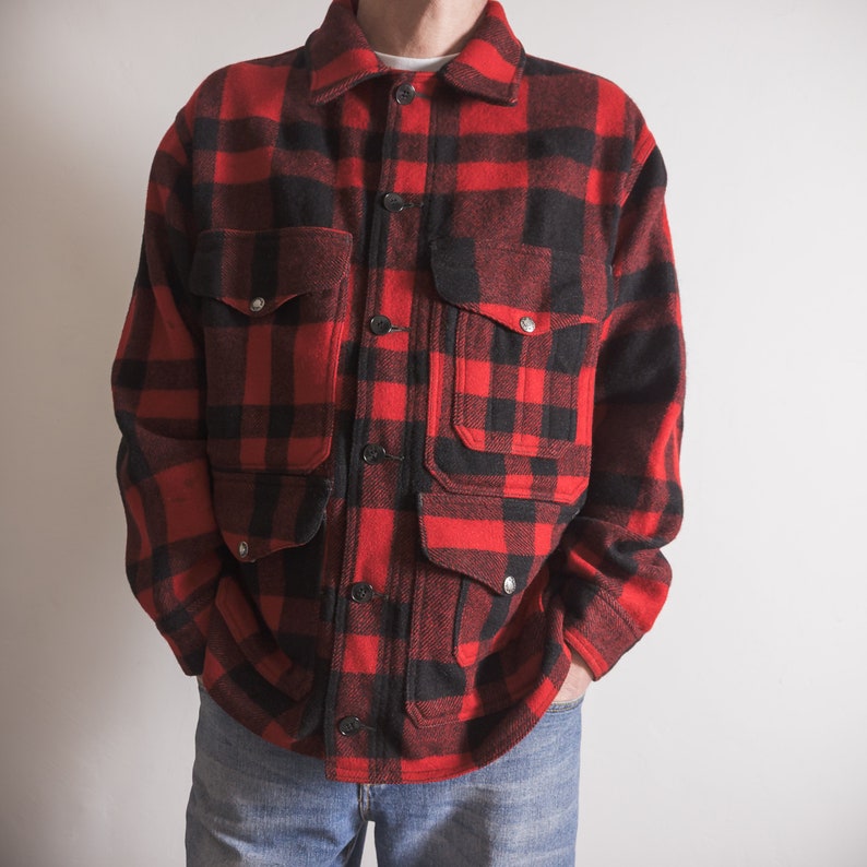 May include: A red and black checked flannel shirt with a button-up front and multiple pockets.