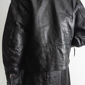 May include: Black leather jacket with a textured finish. The jacket features a classic design with a notched collar, shoulder epaulets, and zippered sleeves. The garment appears to be vintage or pre-owned.