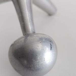 K&ouml;nnte beinhalten: Ein silberfarbenes Metallobjekt mit einer glatten, kugelf&ouml;rmigen Basis, die an einem konischen, zylindrischen Bein befestigt ist. Die Metalloberfl&auml;che weist sichtbare feine Kratzer und ein reflektierendes, poliertes Finish auf.