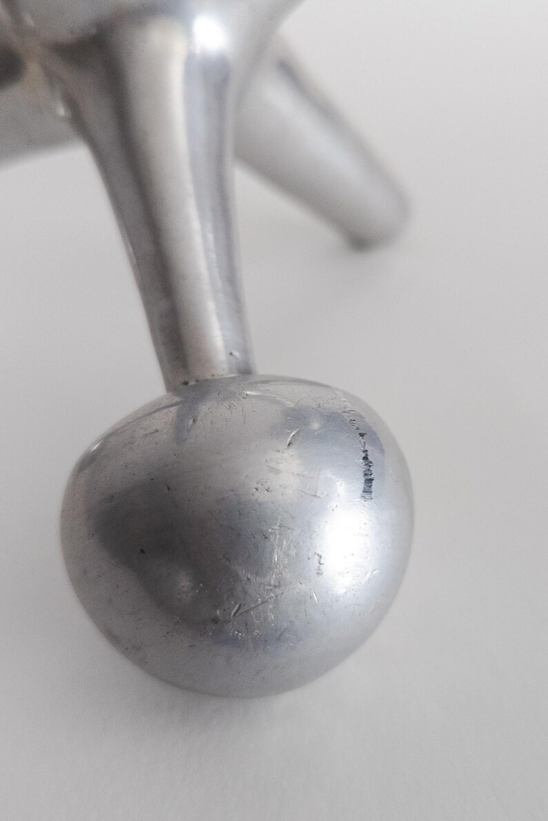 K&ouml;nnte beinhalten: Ein silberfarbenes Metallobjekt mit einer glatten, kugelf&ouml;rmigen Basis, die an einem konischen, zylindrischen Bein befestigt ist. Die Metalloberfl&auml;che weist sichtbare feine Kratzer und ein reflektierendes, poliertes Finish auf.