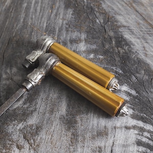 May include: Two antique door knobs with a yellow finish and silver accents. The knobs are on a wooden surface.