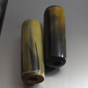 May include: Two brown and black striped cylindrical handles with a hole in the centre.