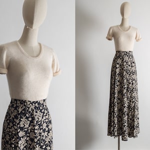 May include: A cream-coloured short-sleeved sweater with a black and white floral print skirt.