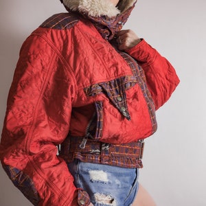 May include: A red quilted jacket with a plaid pattern on the sleeves and a faux fur collar.