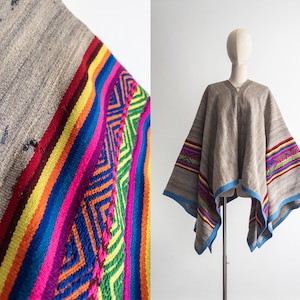 May include: A gray poncho with colorful striped and geometric patterned accents. The poncho has a V-neck and blue trim. The colorful accents include red, yellow, orange, blue, green, and pink stripes and geometric designs.