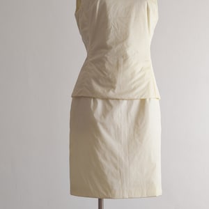 May include: A sleeveless, ivory-colored dress with a fitted bodice and a slightly flared skirt.