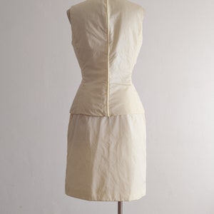 May include: A sleeveless dress in a pale yellow color. The dress has a fitted bodice and a full skirt. The dress is on a mannequin.