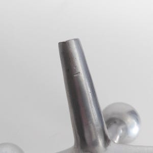 K&ouml;nnte beinhalten: Eine silberfarbene Metallskulptur in Form eines Springerspiels mit einem zentralen Knotenpunkt und sechs strahlenf&ouml;rmigen Armen, die jeweils in einer glatten, kugelf&ouml;rmigen Kugel enden. Die Metalloberfl&auml;che ist matt mit subtilen Lichtreflexen.
