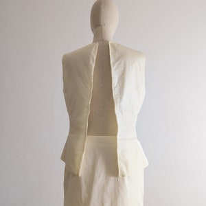 May include: A sleeveless white dress with a peplum skirt and a zipper down the back.
