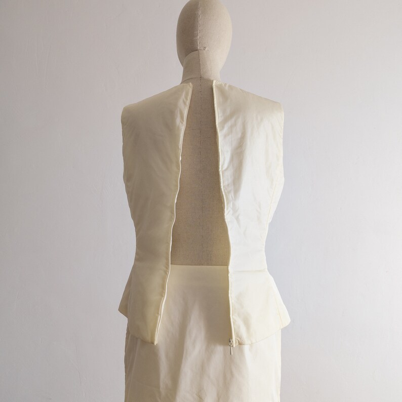 May include: A sleeveless white dress with a peplum skirt and a zipper down the back.
