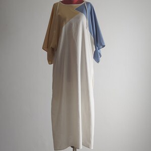 Op de afbeelding: Een witte, gele en blauwe katoenen jurk met een losse pasvorm en korte mouwen. De jurk heeft een eenvoudig ontwerp en is perfect voor een casual look.