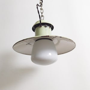 May include: A vintage green and white pendant light with a white frosted glass shade. The light has a simple design with a circular shade and a chain.
