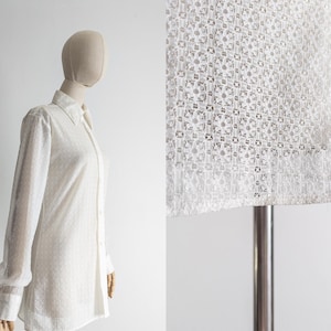 May include: White long-sleeve button-down shirt with a textured, geometric pattern. The shirt features a classic collar and buttoned cuffs. The fabric appears semi-sheer, and the shirt is displayed on a mannequin.