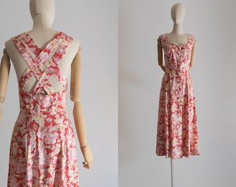 May include: A red and white floral print midi dress with a criss-cross strap back.