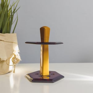 May include: A wooden and purple glass stand with a hexagonal base and a round top. The stand has a decorative design with a wooden post and a purple glass top.