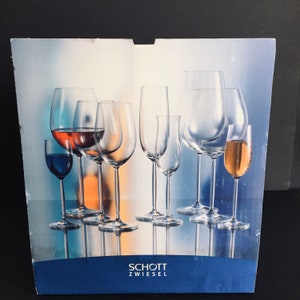 May include: A box of Schott Zwiesel glassware featuring a variety of wine glasses, including a red wine glass, a white wine glass, a champagne flute, and a sherry glass.