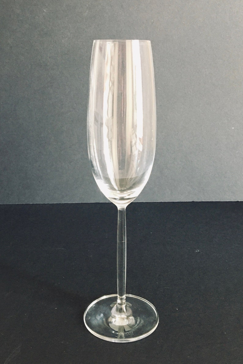 May include: A clear glass champagne flute with a long stem and a wide base.